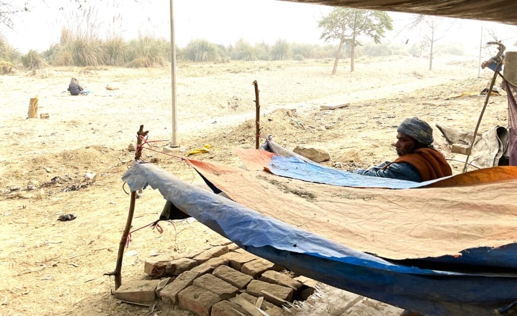 A farmer sitting beside a demolished structure