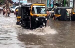 auto rickshaw wading through water in floods in mumbai
