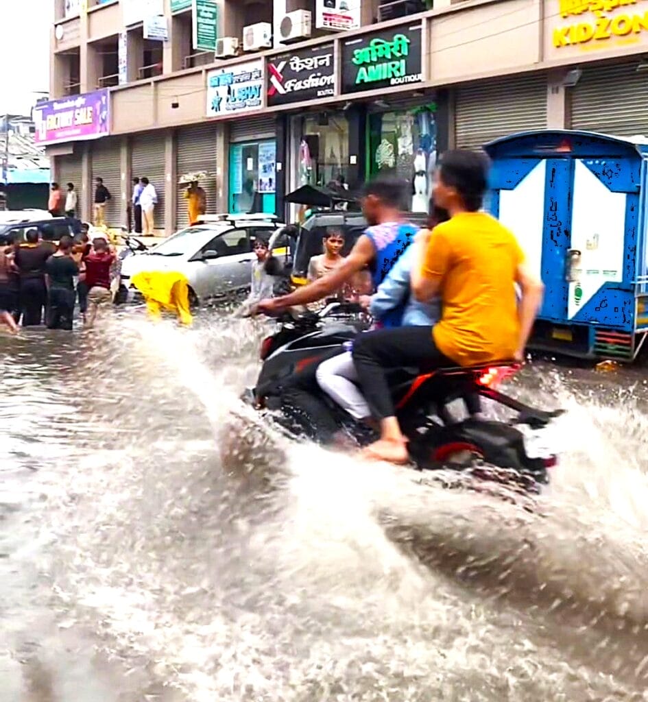 people riding a scooter through flooded Mumbai streets