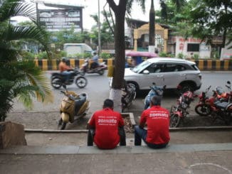Zomato delivery partners sitting by a pavement