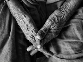 two hands of elderly person interlocked in a black and white image