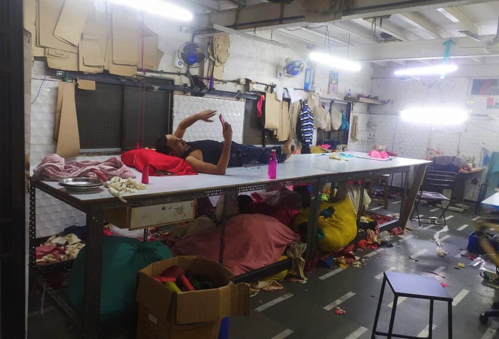 a garment worker in Dharavi taking a break on a table where he is working