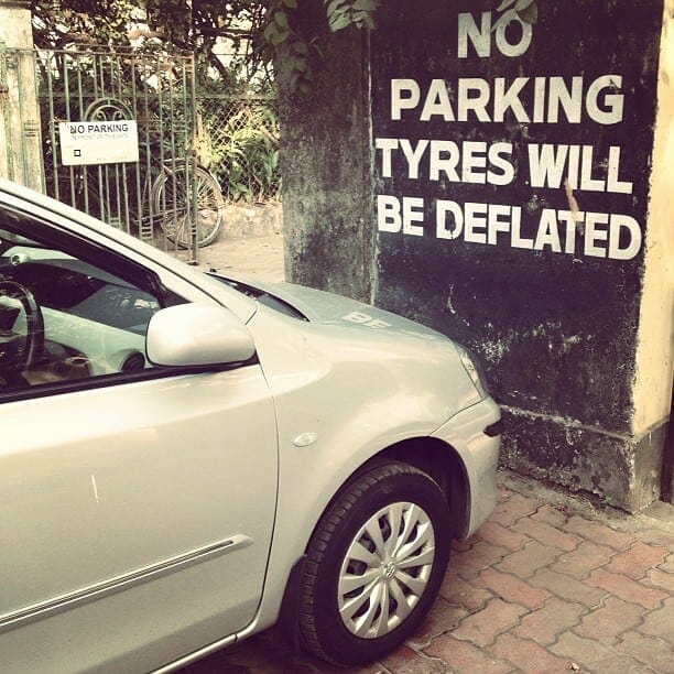 A car in South Bombay parked by a no parking sign