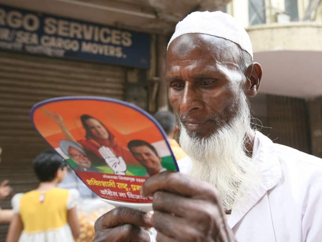 a man reads a political pamphlet distributed at an election rally in India