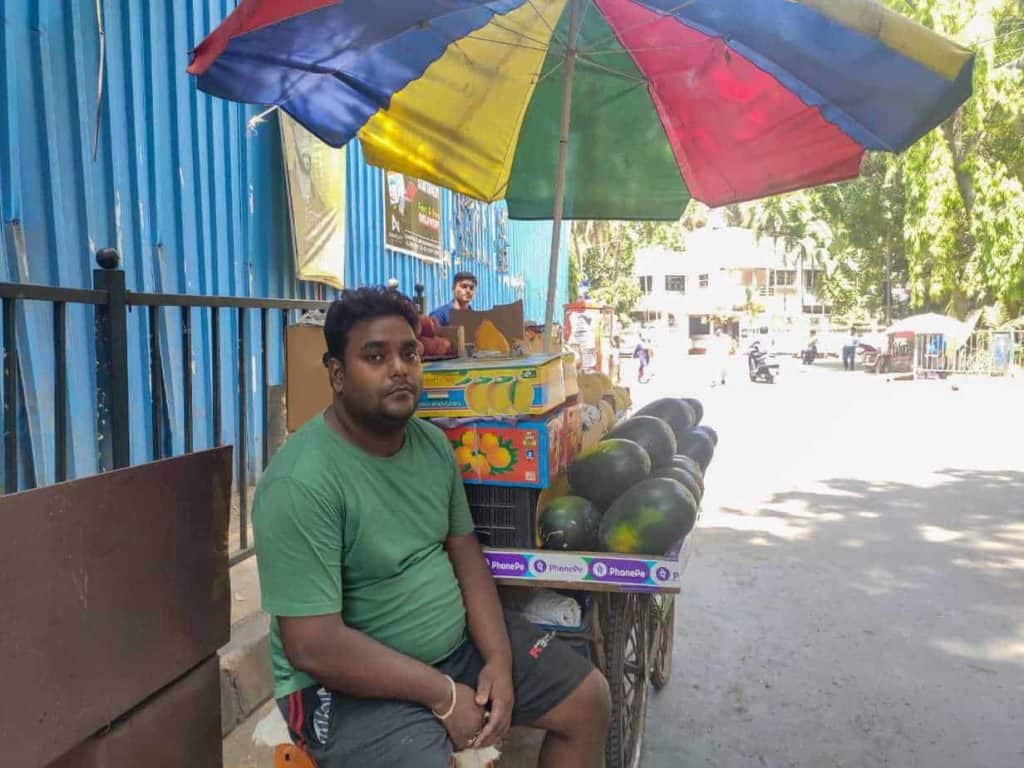 A street vendor in Mumbai has put up an umbrella to shield himself from the heat.