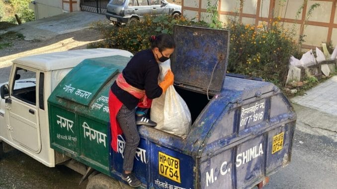 A female waste worker collecting and loading garbage 